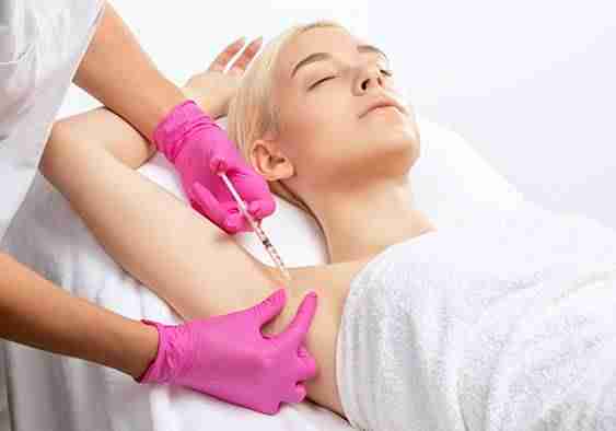 woman in towel relaxing as she receives a botox injection