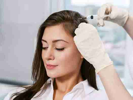 a woman getting her hair restoration treatment done by a phycician