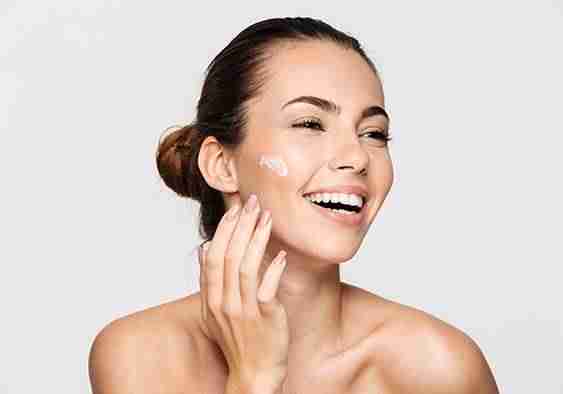 a woman applying cream on her face after microneedling treatment